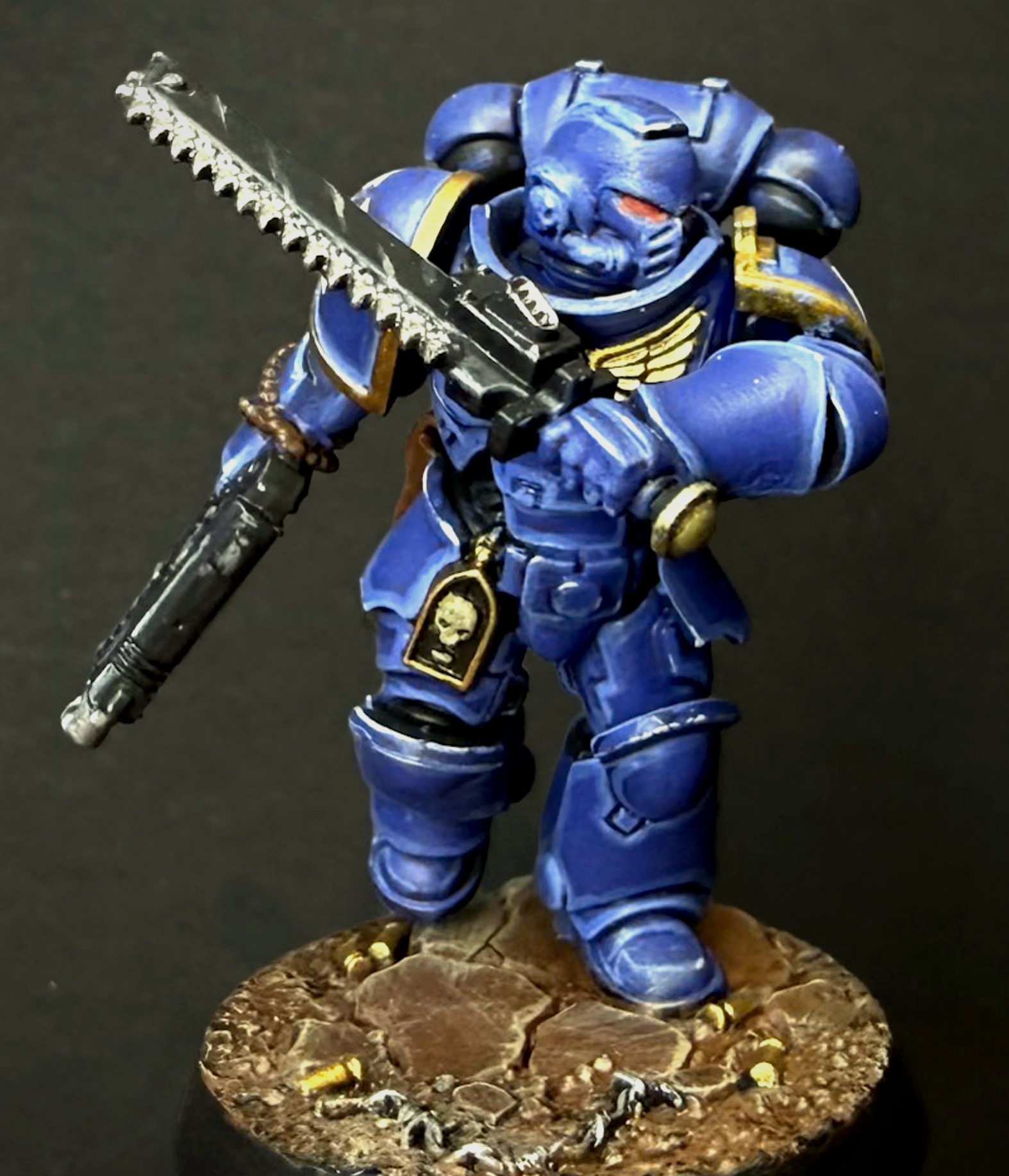 Painted Ultramarines Intercessor with a chainsword raised, blue and gold trim